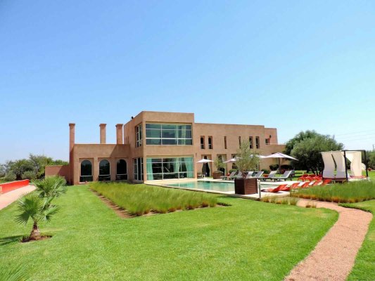 BAB ATLAS au sein du secteur le plus recherché de la palmeraie, superbe villa de maitre aux lignes épurée empreinte de modernité 800 m2 de surface utile bâtie sur un parc de 12 000 m2 , 6 suites dont une master suite de 70 m2 , piscine intérieure chauffée , grande piscine extérieure, hammam, 1 court de tennis et 2 chambres du personnel